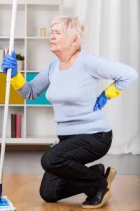 Elderly woman having back pain while cleaning